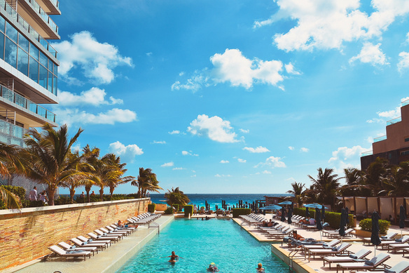 People Enjoying the Swimming Pool Near the Beach Under the Blue Sky